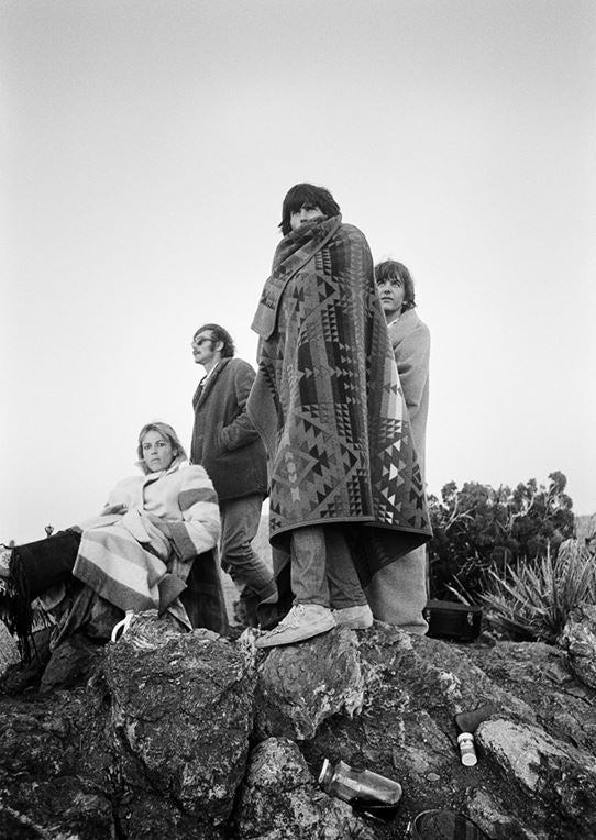 Keith Richards, Anita Pallenberg and Gram Parsons wrapped in an Indian blanket at Joshua Tree, California, photographed by Michael Cooper, 1968.