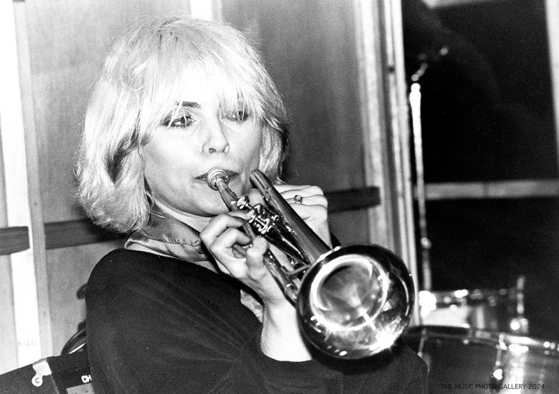 Debbie Harry holding a trumpet during a live performance, photographed by Ebet Roberts.