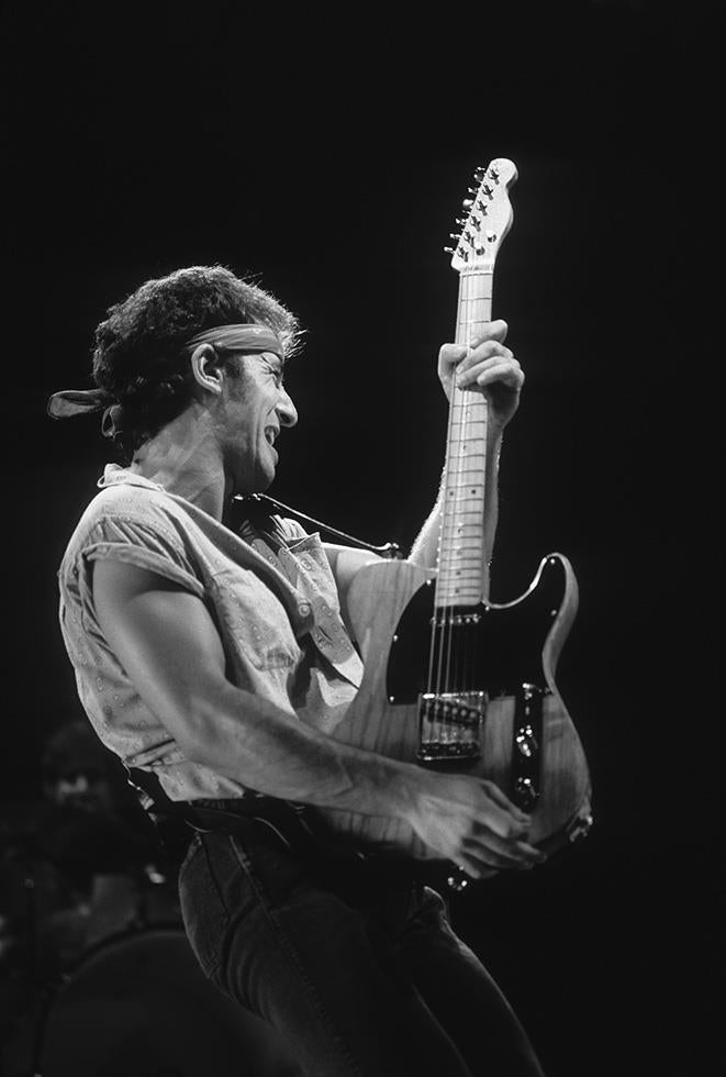 Bruce Springsteen playing his Telecaster on stage wearing a headband, photographed by Charlyn Zlotnik.