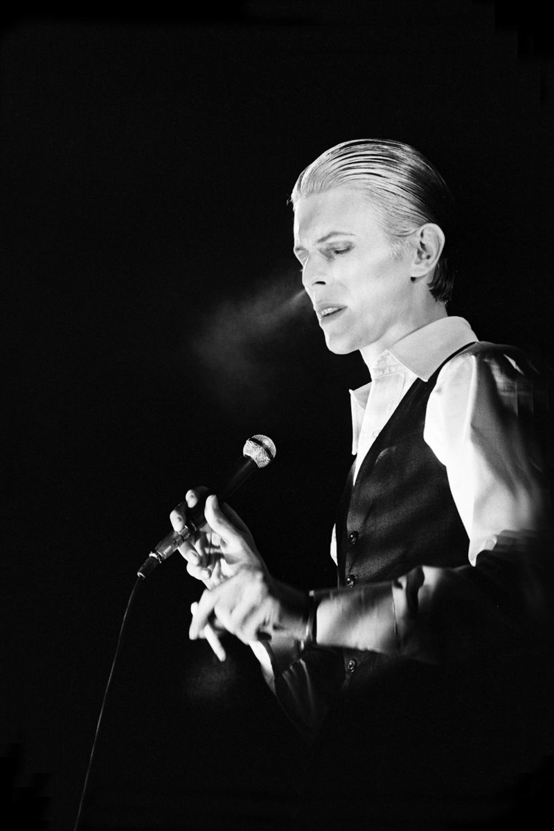David Bowie paused beside a microphone with his hands together in 1976. Photograph by Gijsbert Hanekroot.