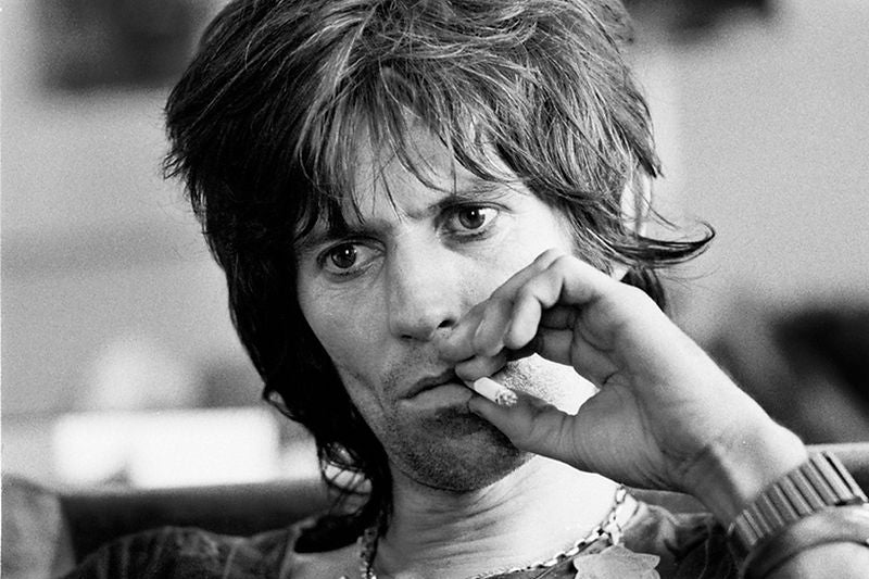 Keith Richards in a close-up portrait with one hand near his face in 1976. Photograph by Gijsbert Hanekroot.