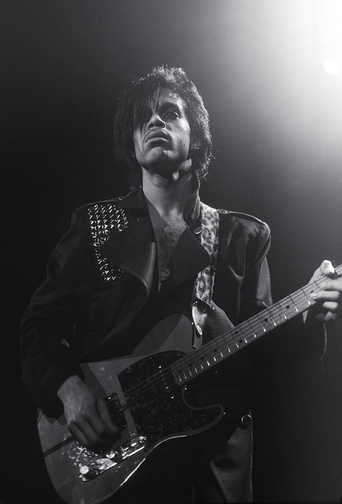 Prince performing on stage with his guitar, photographed by Charlyn Zlotnik.