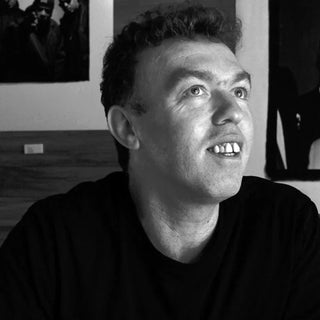 Black-and-white portrait of photographer David Corio smiling and looking upward.