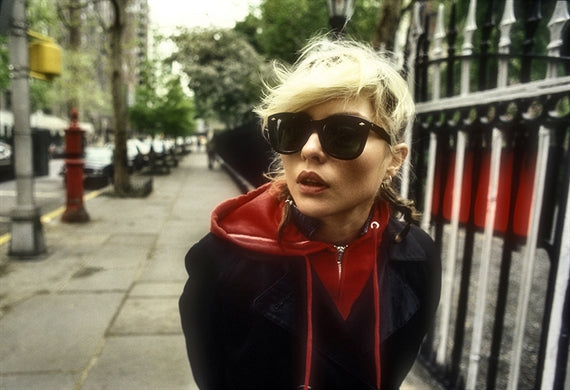 Debbie Harry in sunglasses and a red hooded top on the street by Gramercy Park, New York, photographed by Martyn Goddard, 1978.