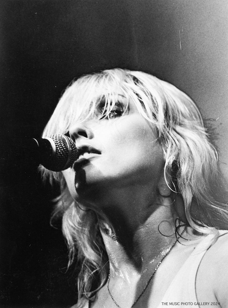 Debbie Harry singing into a handheld microphone, photographed by Ebet Roberts.