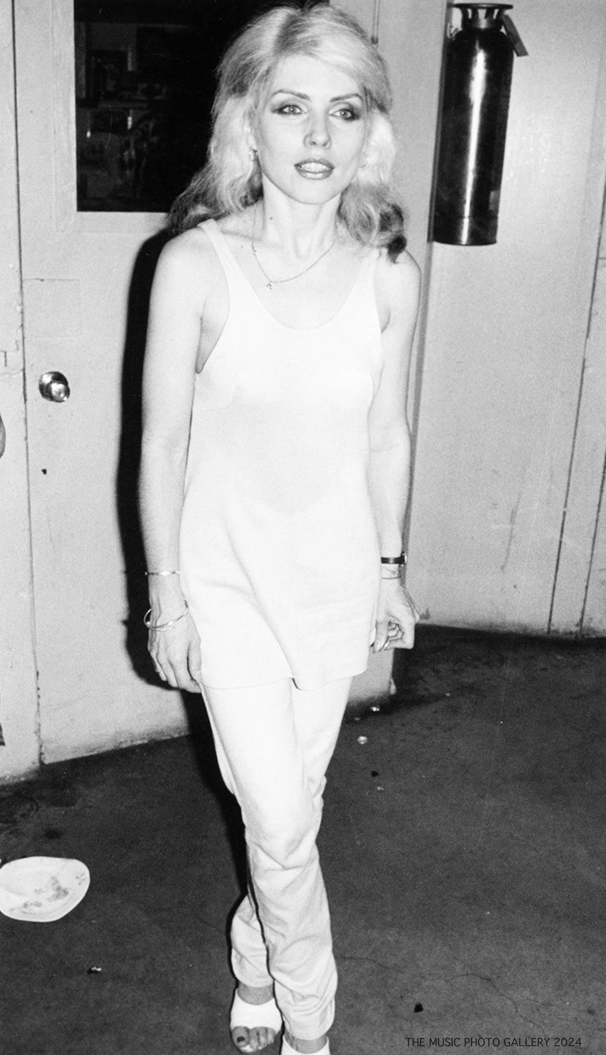 Debbie Harry standing backstage in a full-length portrait, photographed by Ebet Roberts.