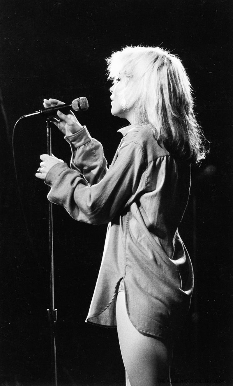 Debbie Harry standing at a microphone, photographed by Ebet Roberts.