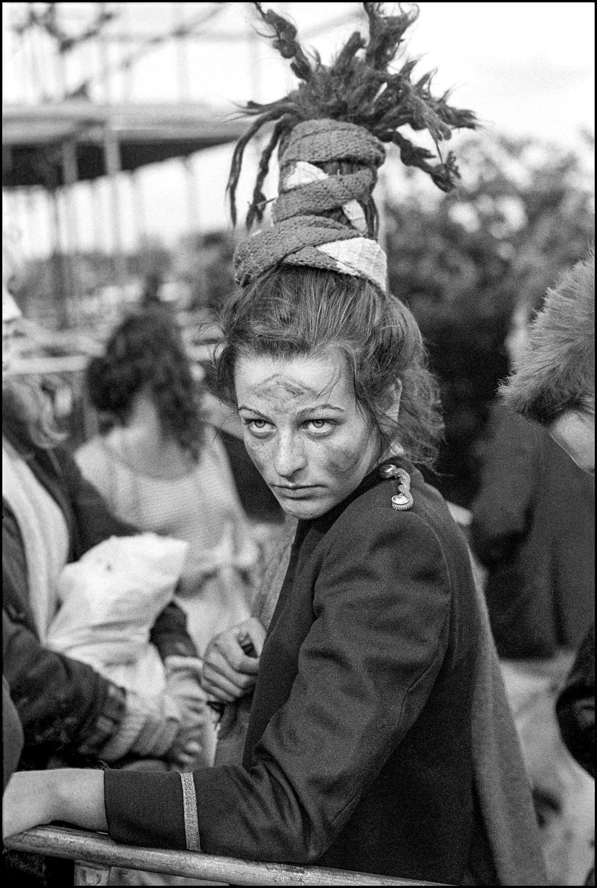 Ari Up of The Slits with wrapped dreadlocks and painted face looking over her shoulder backstage at Alexandra Palace, London, 1980, photographed by David Corio.