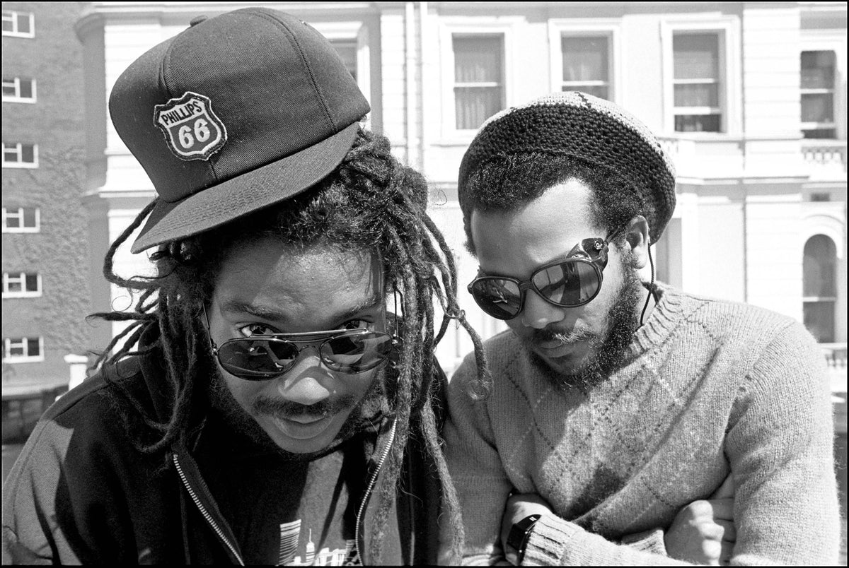 Dr. Know and Darryl Jenifer of Bad Brains in sunglasses leaning together outside the Lancaster Gate Hotel, London, 1987, photographed by David Corio.