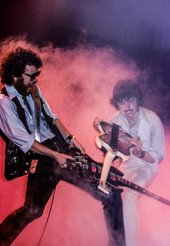 Blue Öyster Cult playing guitar through pink stage smoke, in color, 1978, photographed by Lynn Goldsmith.