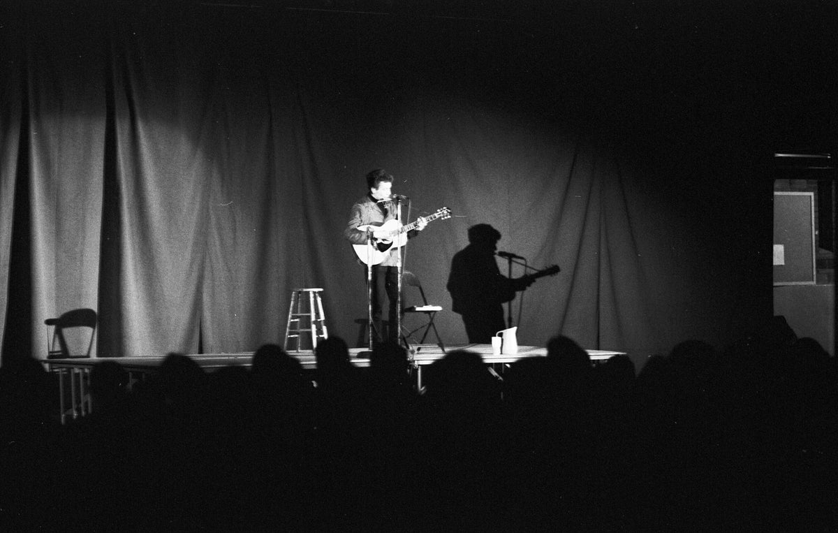 Bob Dylan and His Shadow on Stage, Unknown Location, 1964; photograph by John Byrne Cooke.