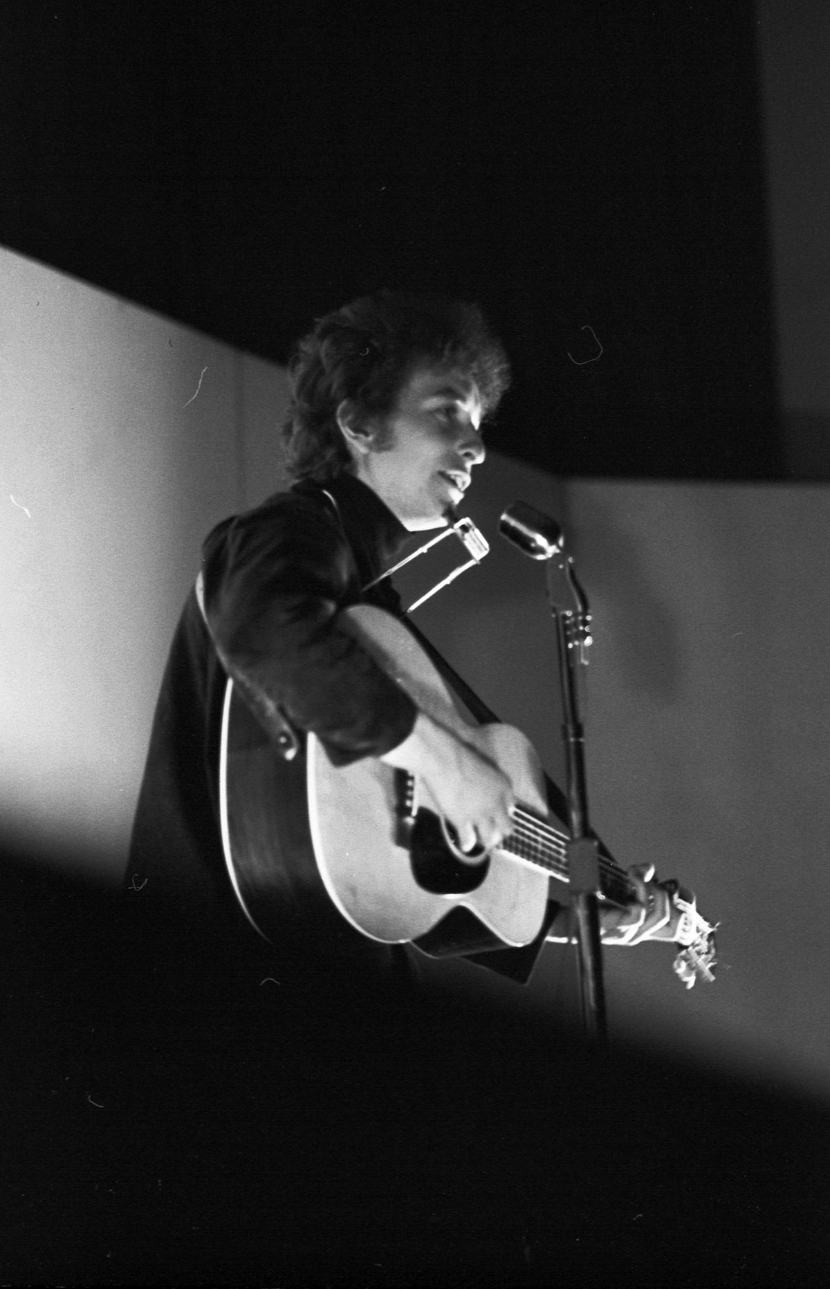 Bob Dylan Singing in the Spotlight, Unknown Location, 1964; photograph by John Byrne Cooke.