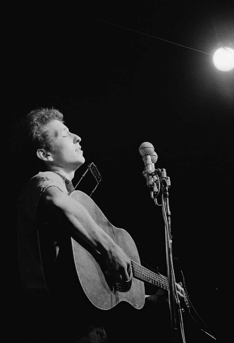 Bob Dylan performing with acoustic guitar and harmonica at the Newport Folk Festival in 1963, photographed by Rowland Scherman.