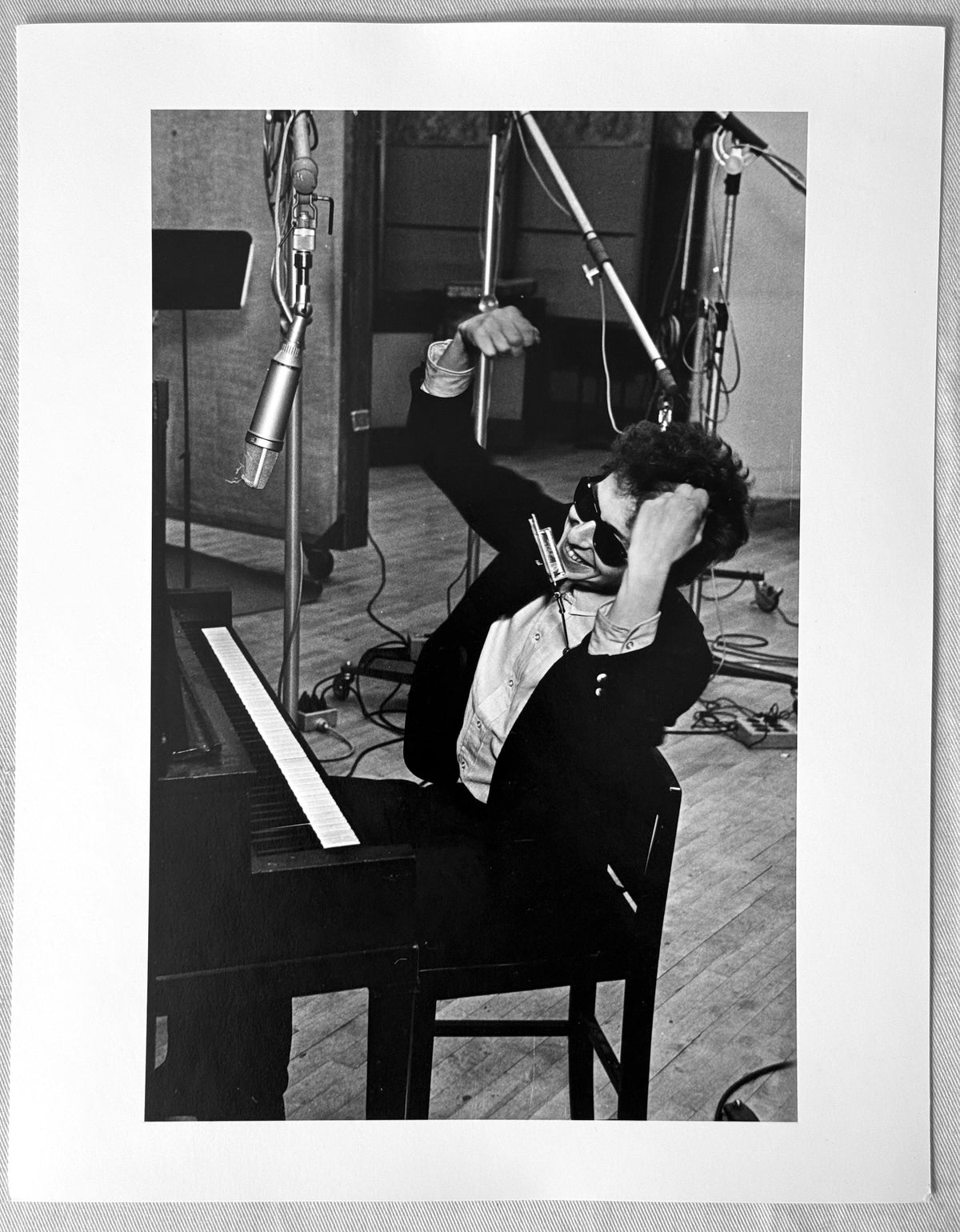Vintage gelatin silver print of Bob Dylan stretching at the piano, one arm raised, in Columbia Studio A, New York City, 1965, photographed by Daniel Kramer.