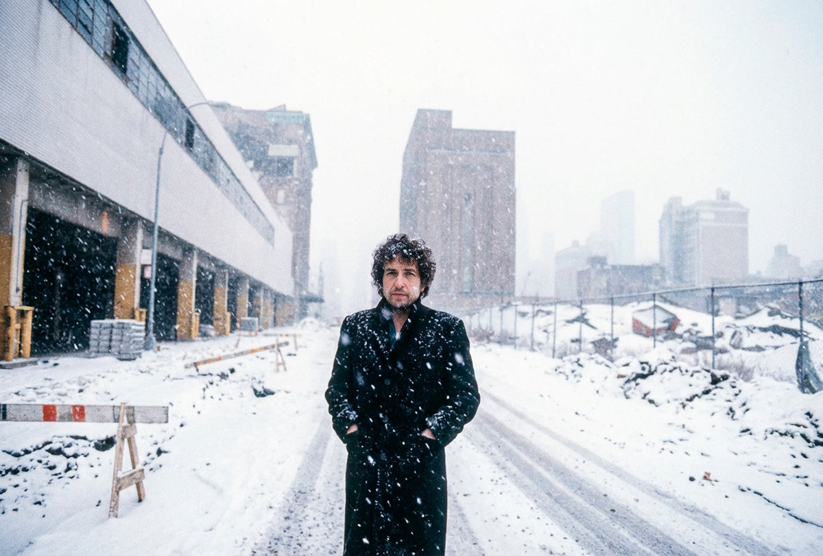 Bob Dylan standing in falling snow on the West Side of New York City, 1983, photographed by Lynn Goldsmith.