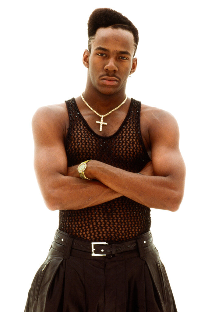 Bobby Brown with arms crossed against a white background, in color, 1990, photographed by Lynn Goldsmith.