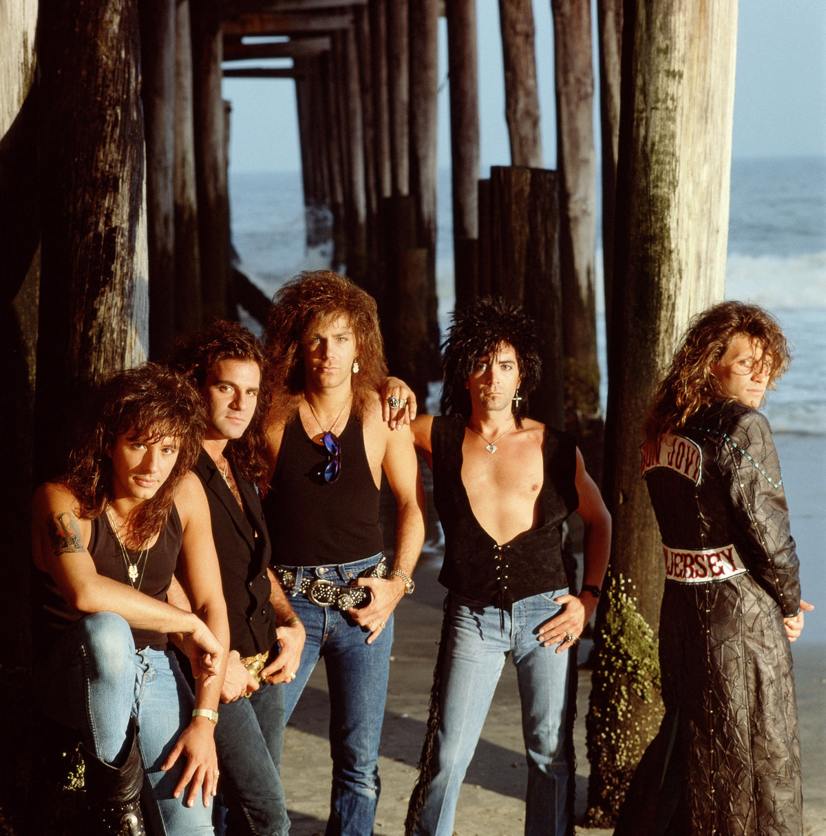 The members of Bon Jovi gather beneath the timber structure of a seaside pier. Photograph by Timothy White, Seaside Heights, New Jersey, 1988.