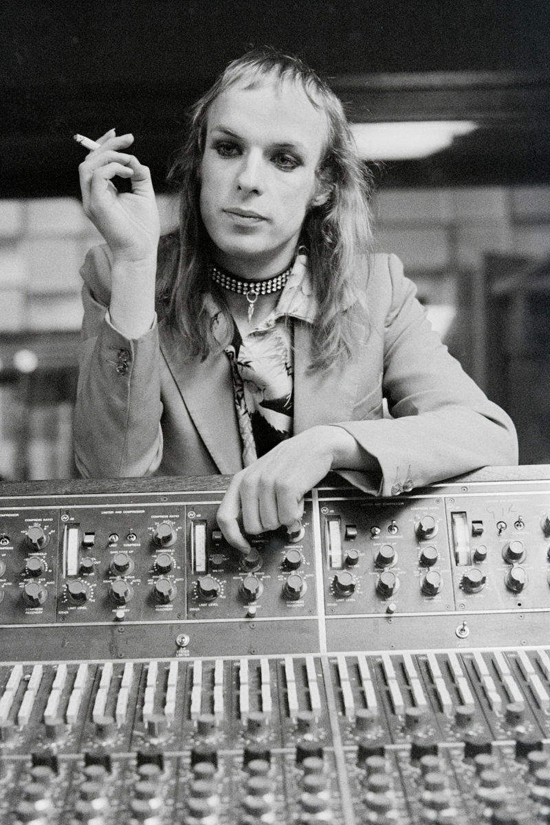 Brian Eno seated behind a mixing console and holding a cigarette in 1973. Photograph by Gijsbert Hanekroot.