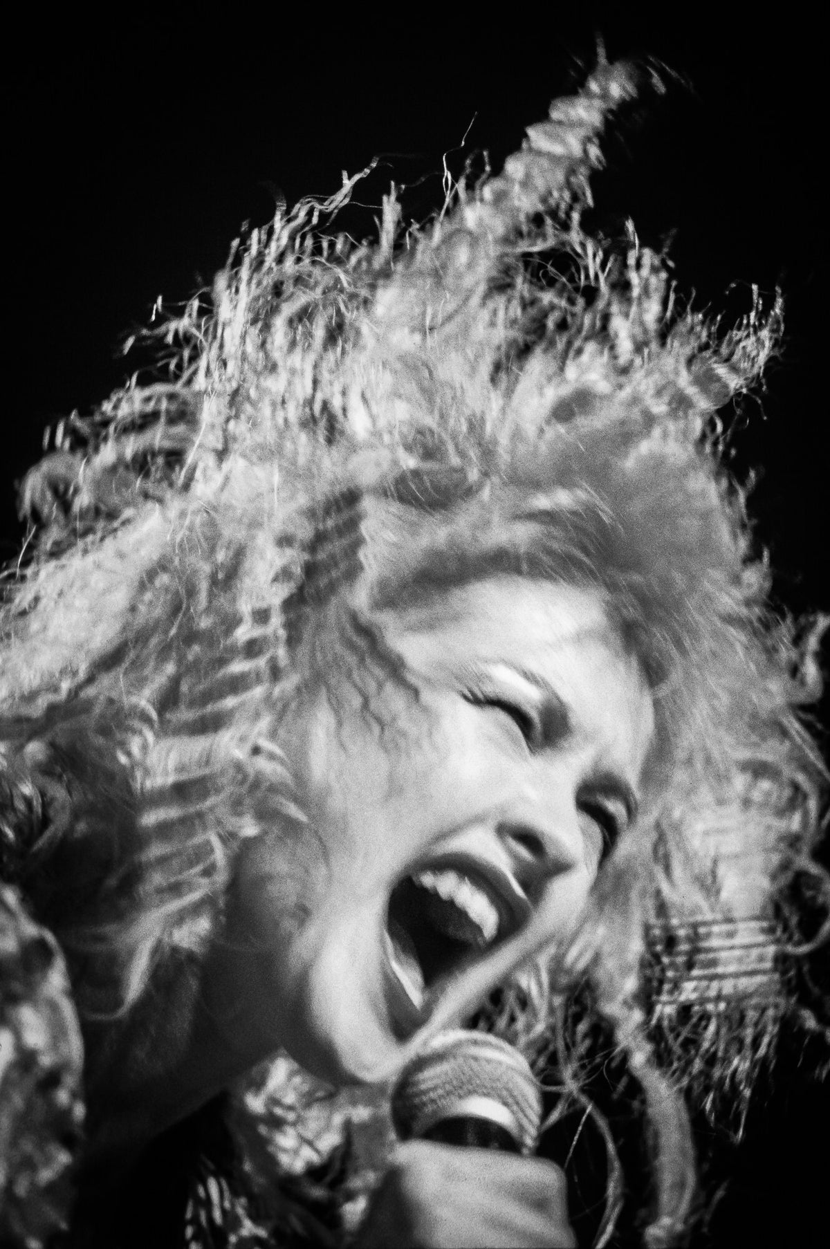 Cyndi Lauper singing with hair flying, in black and white, 1989, photographed by Lynn Goldsmith.