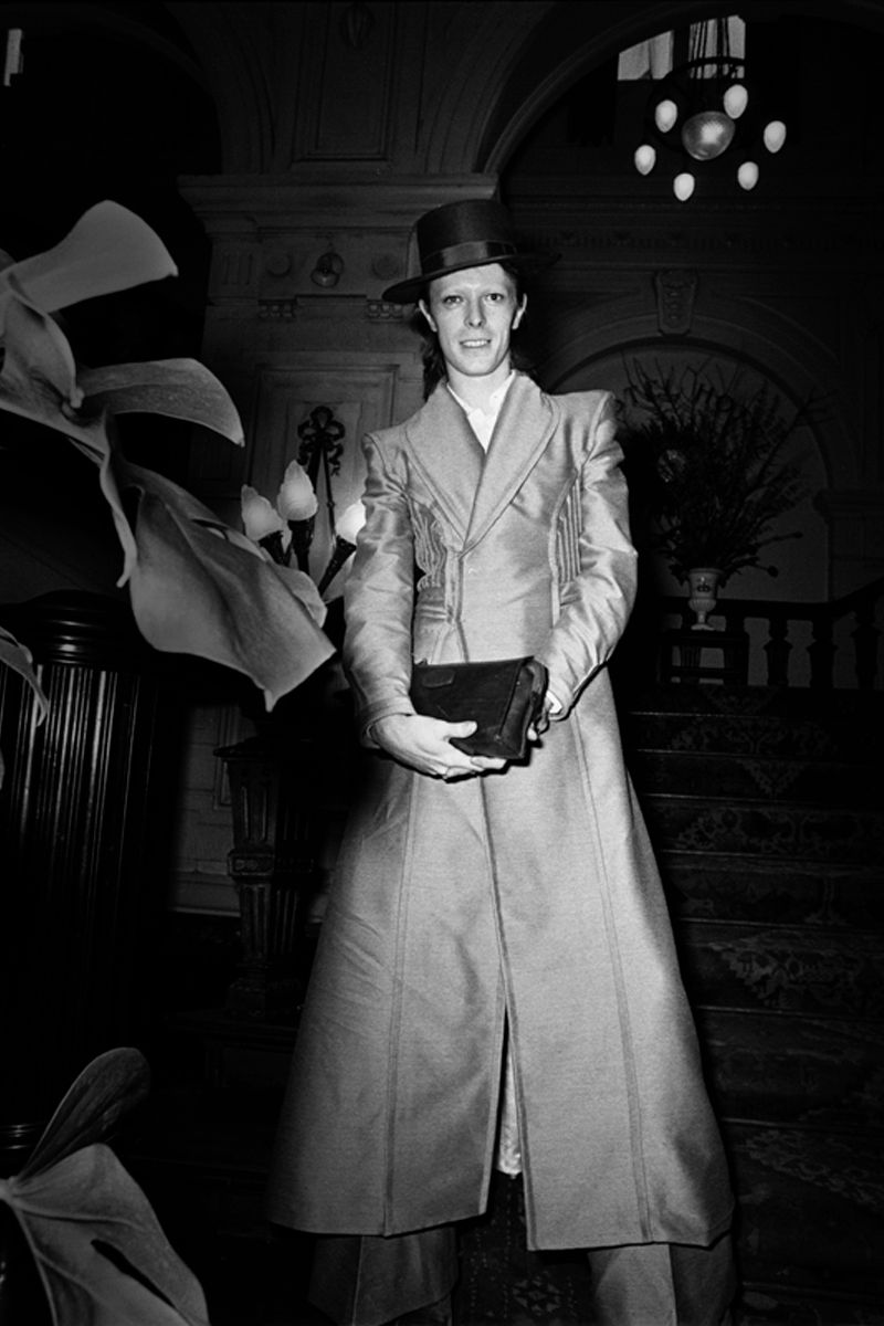David Bowie posed indoors in a long coat and hat in 1972. Photograph by Gijsbert Hanekroot.