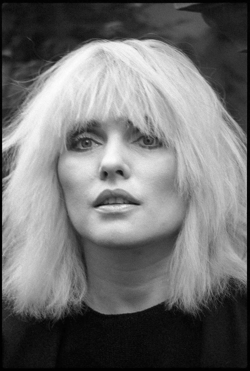 Close-up black and white portrait of Debbie Harry with platinum blonde hair and fringe, Ritz Hotel, London, 1983, photographed by David Corio.