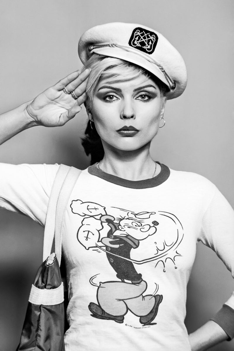 Debbie Harry of Blondie saluting in a sailor cap and Popeye T-shirt, 1978, photographed by Lynn Goldsmith.