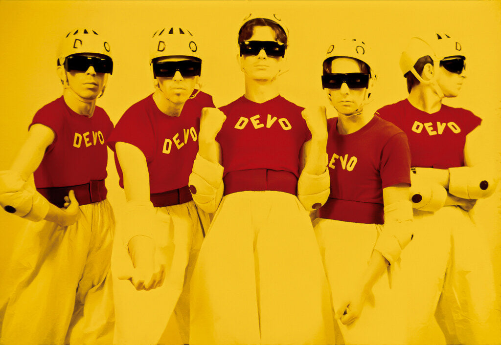 The members of DEVO in matching red shirts and sunglasses against yellow, 1978, photographed by Lynn Goldsmith.