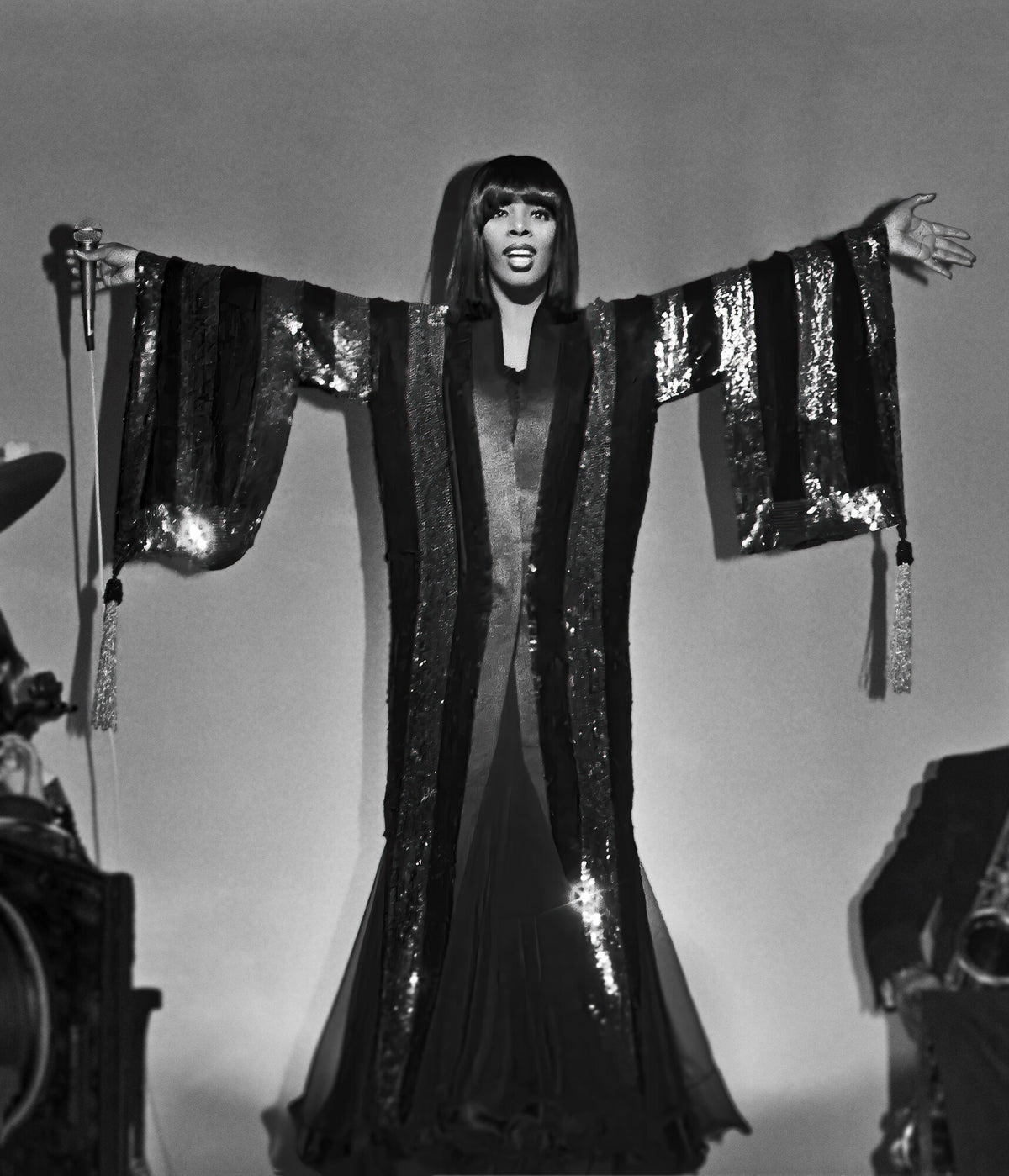 Donna Summer with arms spread wide in a flowing gown, in black and white, 1979, photographed by Lynn Goldsmith.