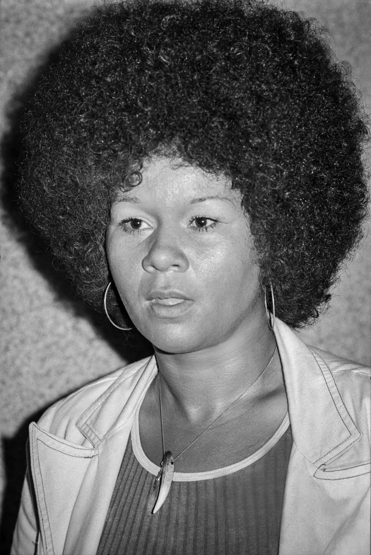 Close portrait of Etta James with a full Afro and hoop earrings, in black and white, 1974, photographed by Lynn Goldsmith.