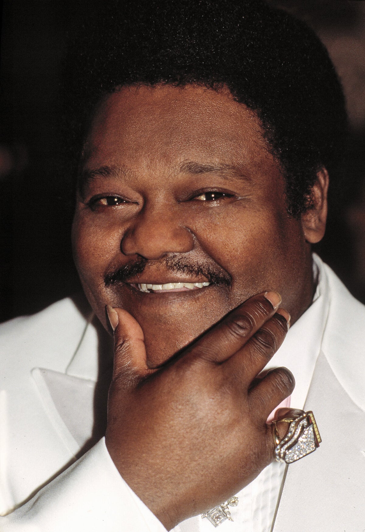 Fats Domino smiling with his chin on his hand, in color, 1986, photographed by Lynn Goldsmith.