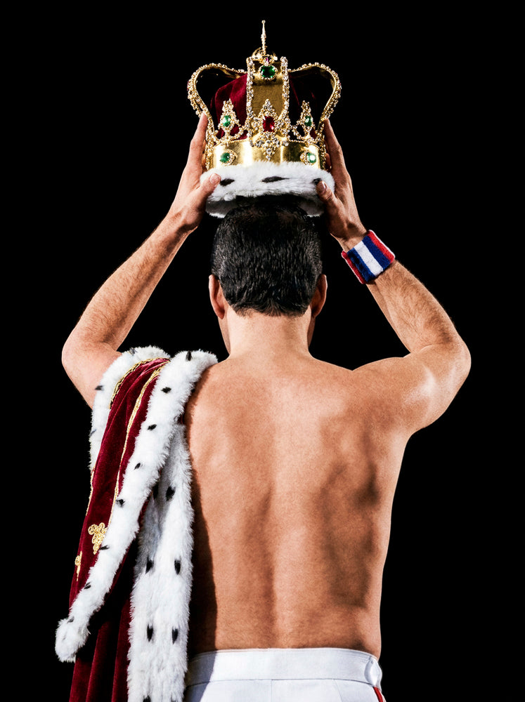 Freddie Mercury of Queen seen from behind, lifting a crown above his head, 1986, photographed by Lynn Goldsmith.