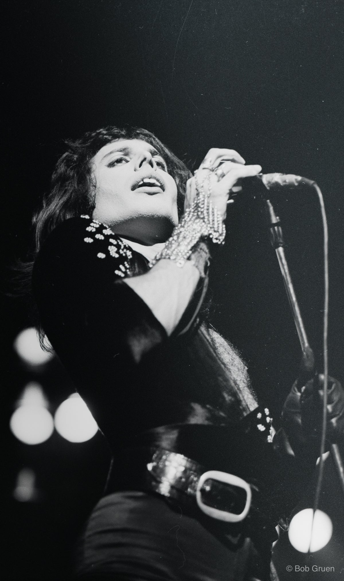 Black-and-white photograph of Freddie Mercury performing live at the Rainbow Theatre, London, March 1974, photographed by Mick Rock.