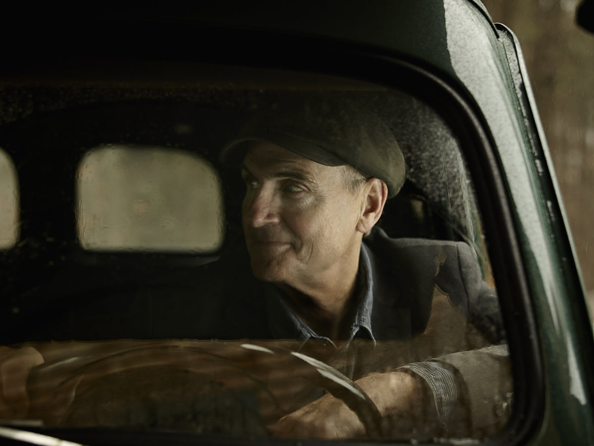 James Taylor looks out through the window of a weathered truck, its curved frame enclosing his portrait. Photograph by Timothy White, Stockbridge, Massachusetts, 2014.