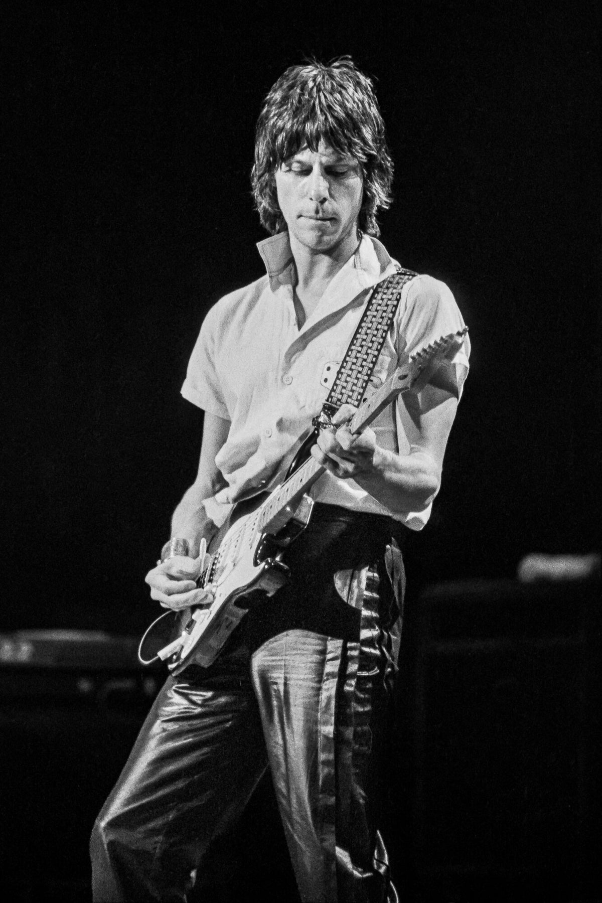 Jeff Beck playing a white electric guitar, in black and white, 1983, photographed by Lynn Goldsmith.