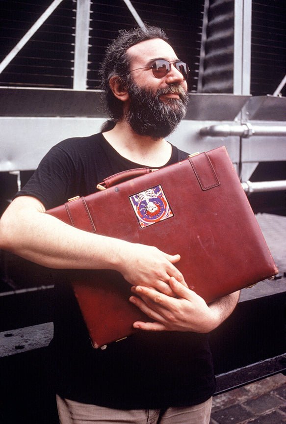 Jerry Garcia of the Grateful Dead holding a briefcase, New York City, 1979, photographed by Mark Weiss.