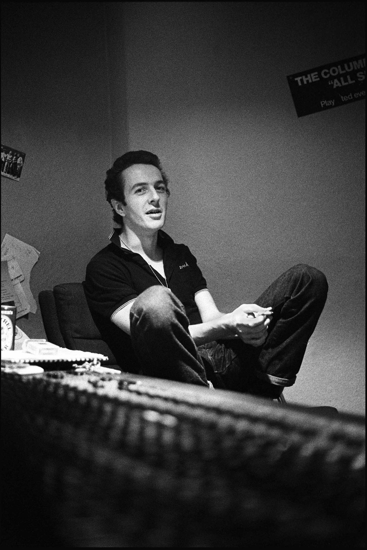 Joe Strummer sitting relaxed behind a mixing desk in a recording studio in Soho, London, 1980, photographed by David Corio.