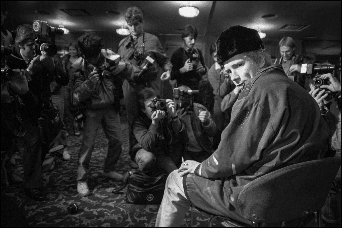 John Lydon looking back over his shoulder as a crowd of press photographers aims their cameras at him, Royal Lancaster Hotel, London, 1983, photographed by David Corio.