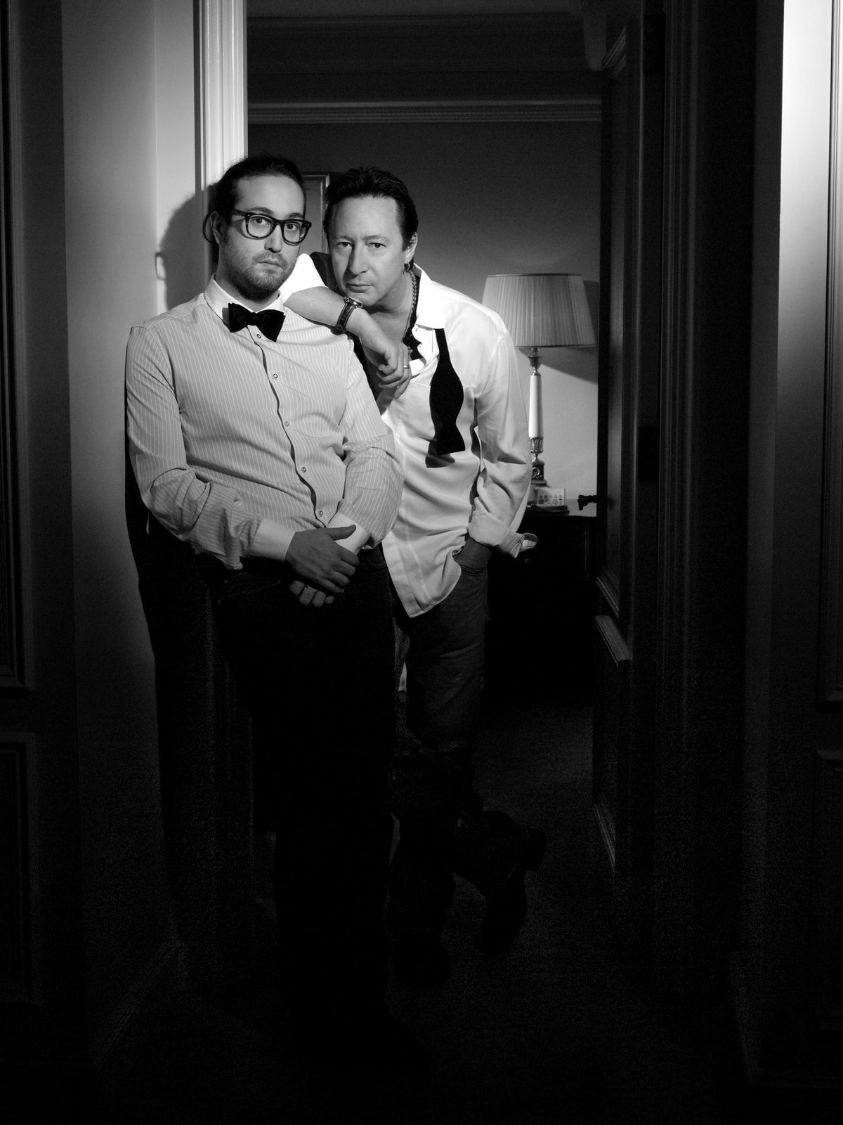 Julian and Sean Lennon stand close together in a narrow doorway, facing the camera. Photograph by Timothy White, New York City, 2009.