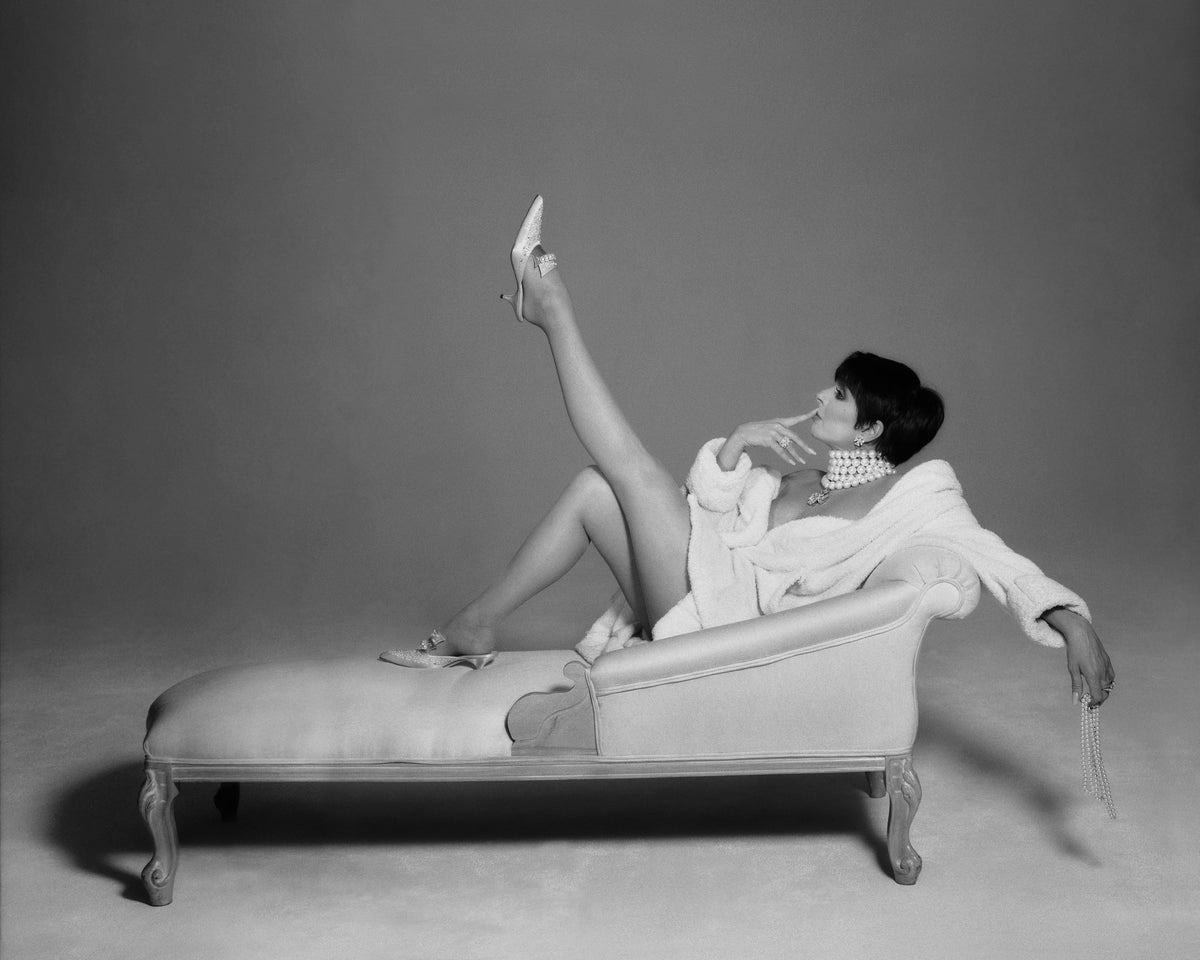 Liza Minnelli reclines on a chaise longue, raising one leg in a theatrical studio pose. Photograph by Timothy White, New York City, 1996.