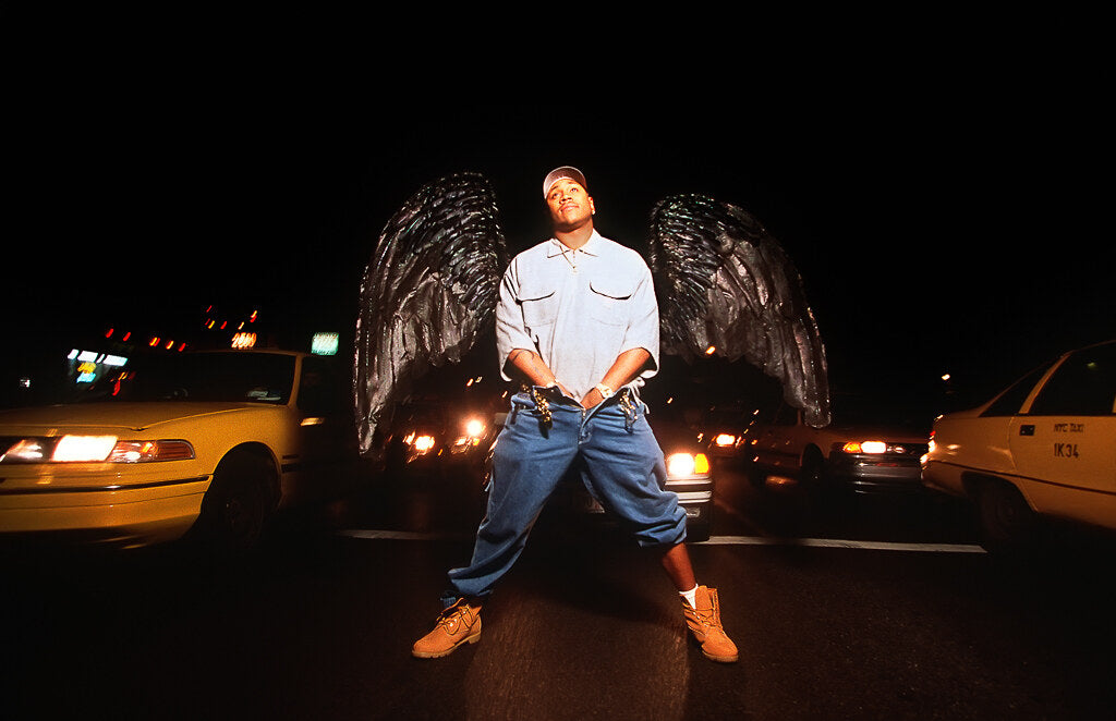 LL Cool J at night between taxis with dark wings behind him, in color, 1997, photographed by Lynn Goldsmith.