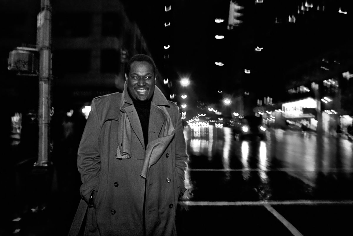 Luther Vandross on a wet city street at night, in black and white, 1982, photographed by Lynn Goldsmith.