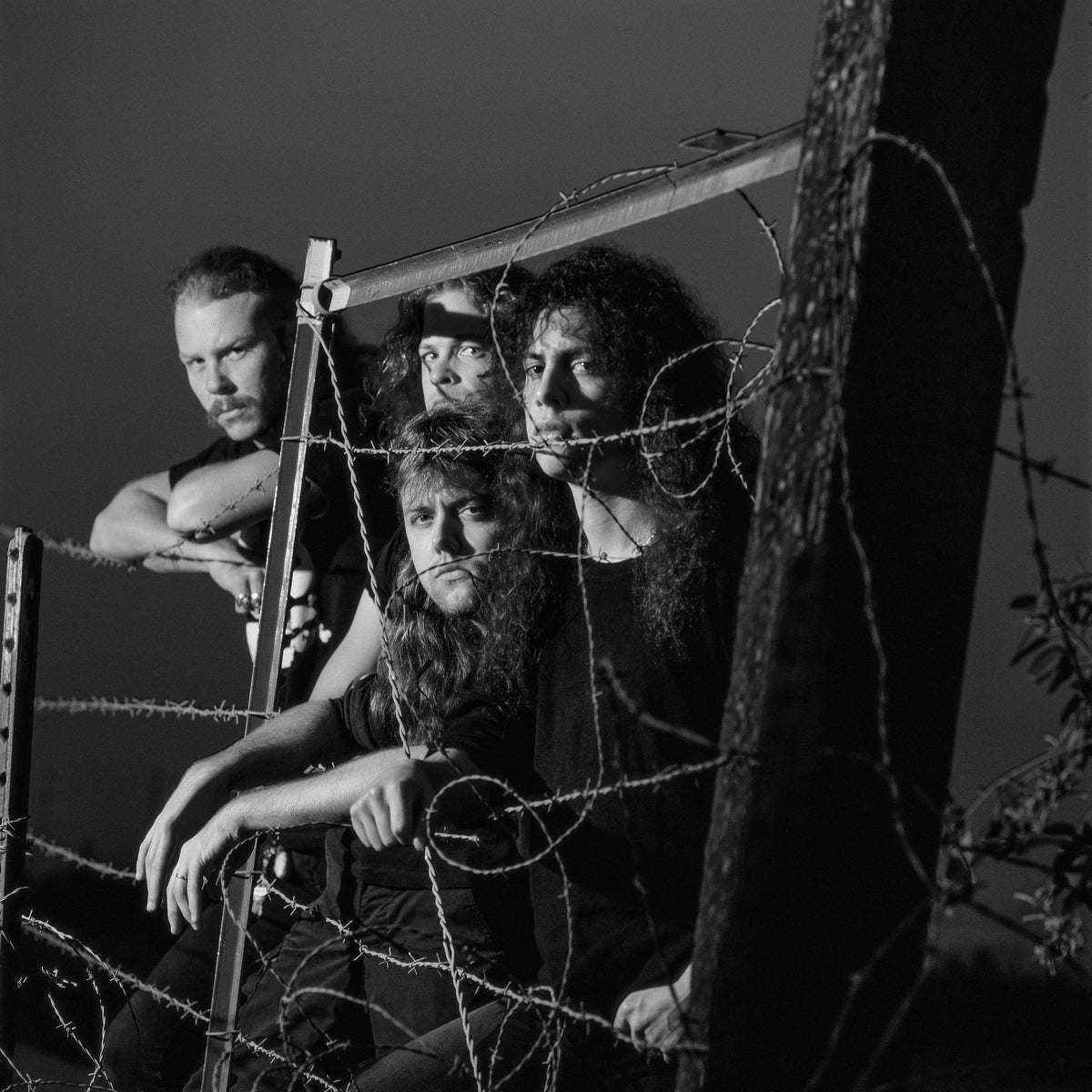The members of Metallica lean through and around a barbed-wire fence in a tightly framed group portrait. Photograph by Timothy White, San Francisco, California, 1989.