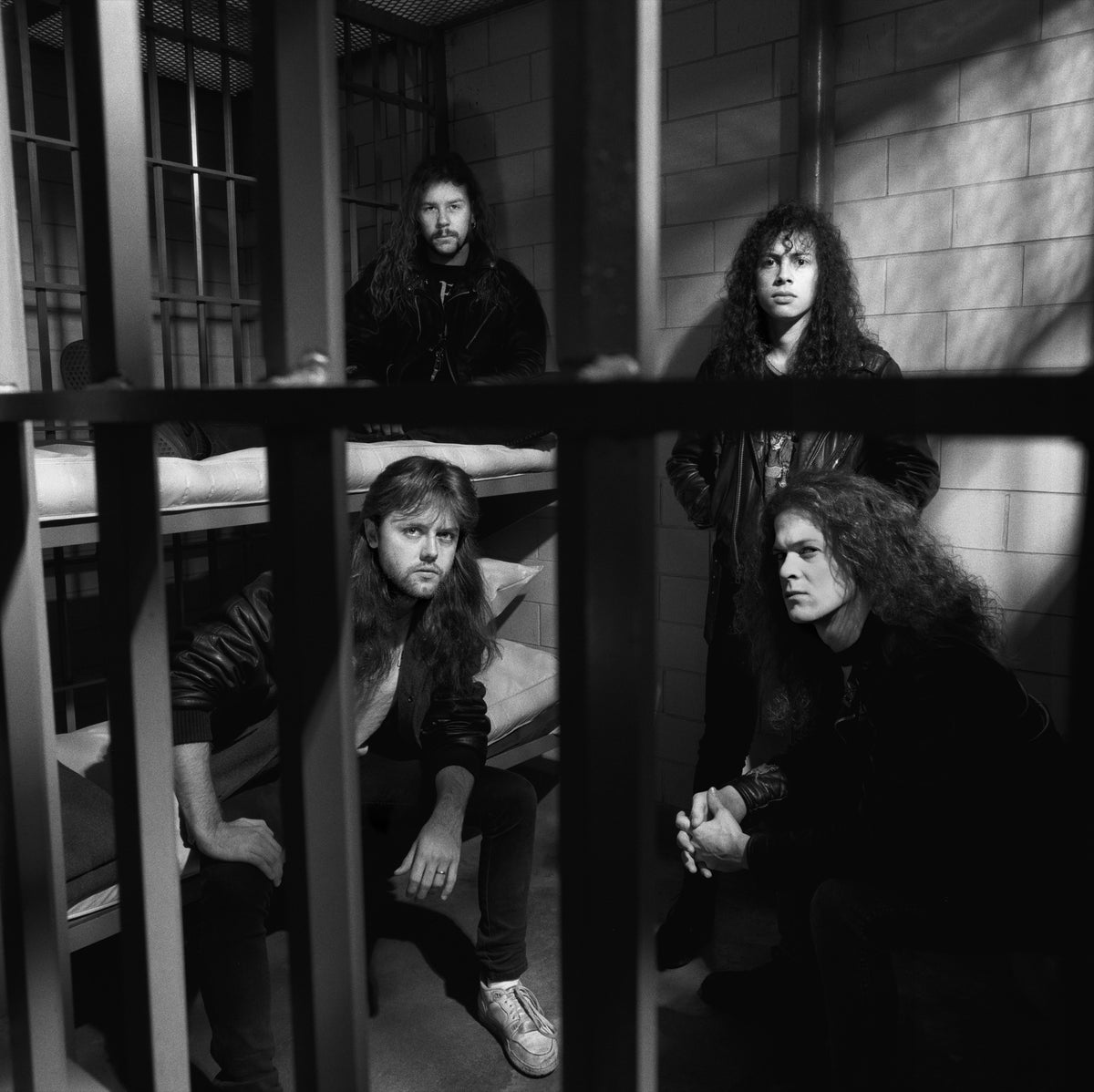 The members of Metallica are framed by the bars and shadowed recesses of a jail setting. Photograph by Timothy White, Shaker Heights, Ohio, 1988.