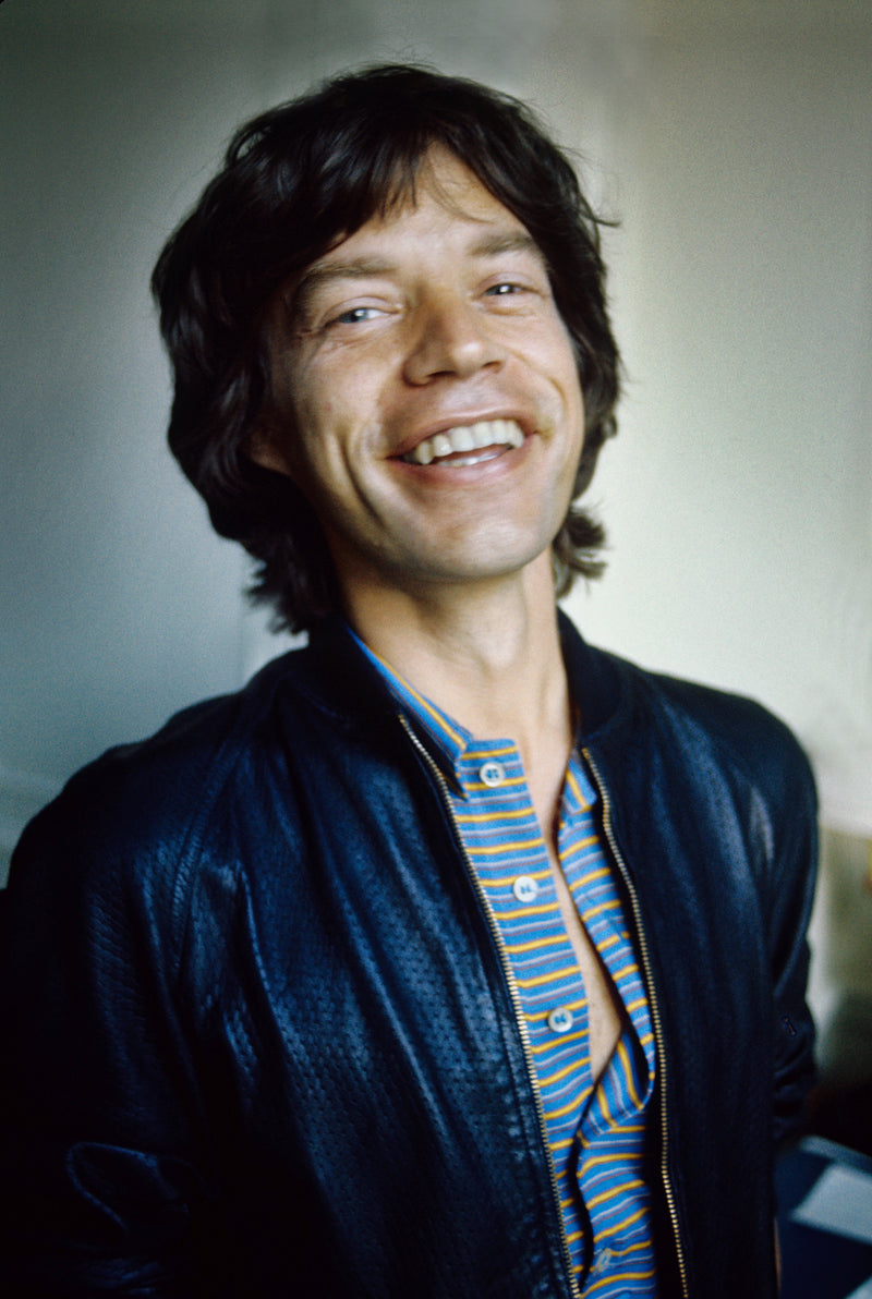 Mick Jagger smiling and looking to one side during a color portrait in 1977. Photograph by Gijsbert Hanekroot.