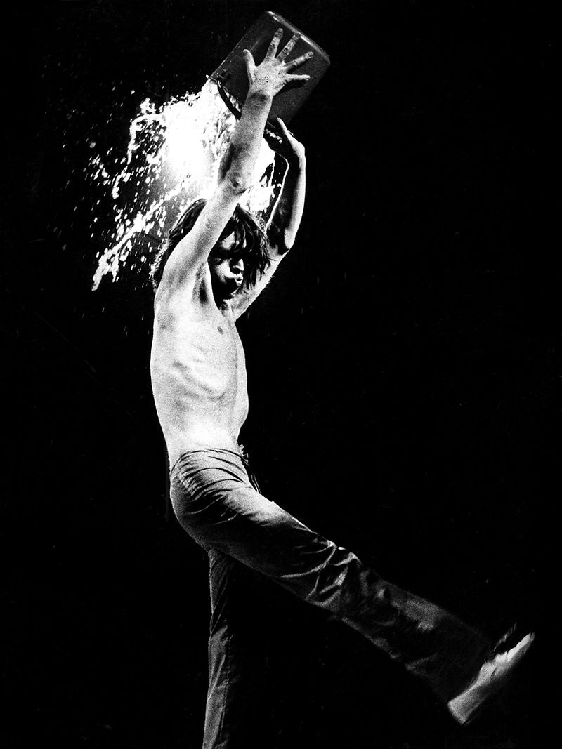 Mick Jagger throwing water overhead during a performance in 1976. Photograph by Gijsbert Hanekroot.