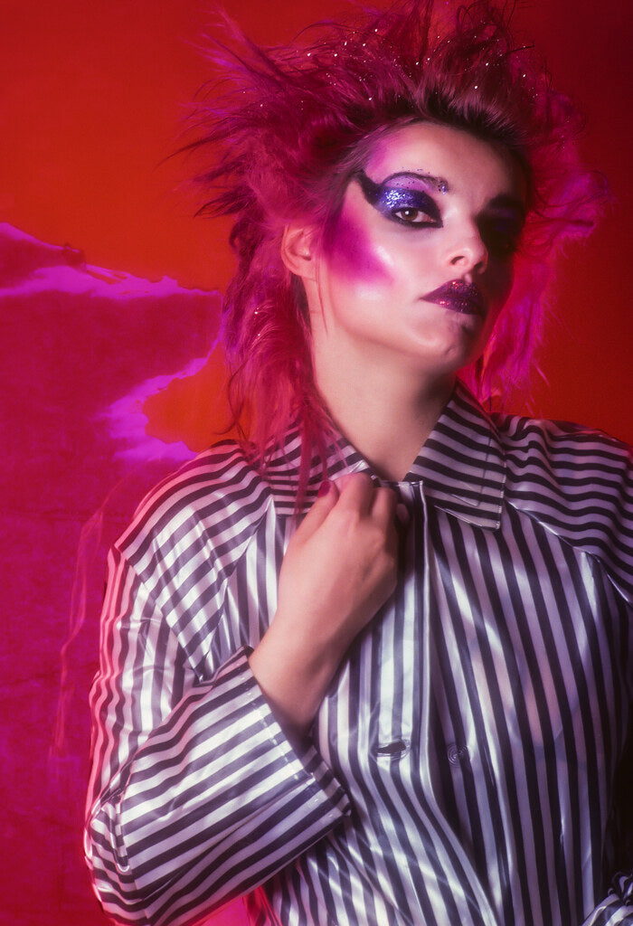 Nina Hagen in bold makeup against red, in color, 1980, photographed by Lynn Goldsmith.