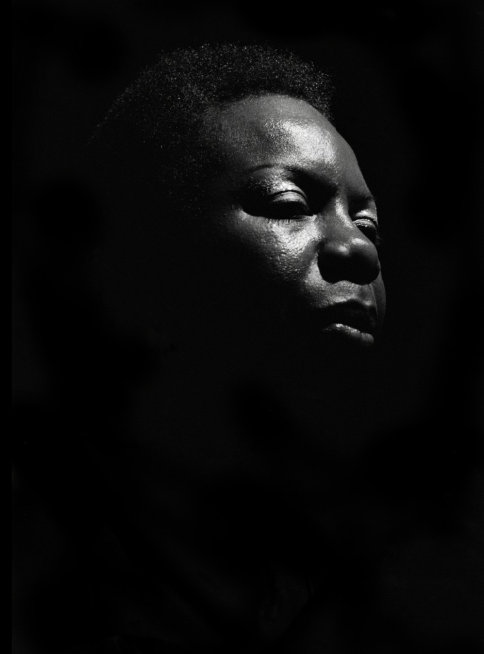 Nina Simone performing under a single spotlight at Ronnie Scott's, London, in 1984, photographed by David Corio.