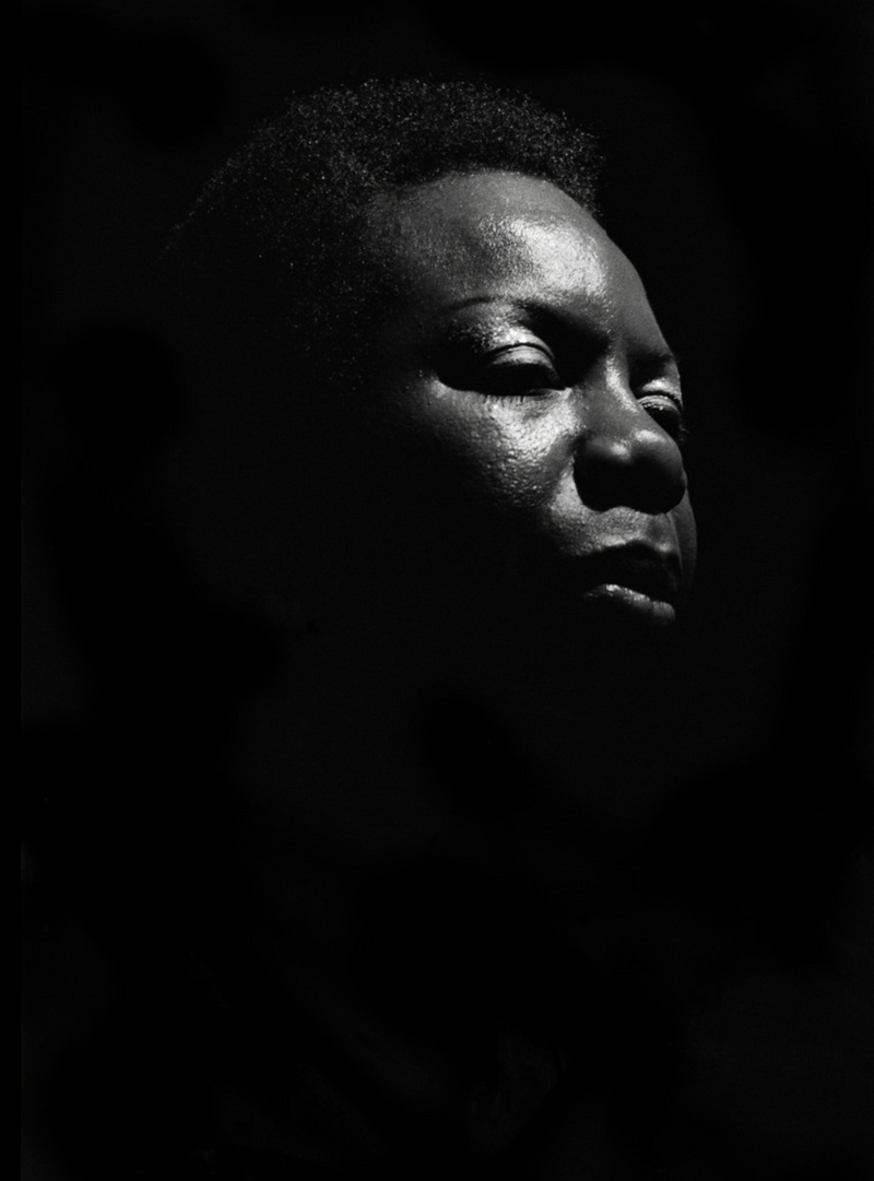 Nina Simone performing under a single spotlight at Ronnie Scott's, London, in 1984, photographed by David Corio.