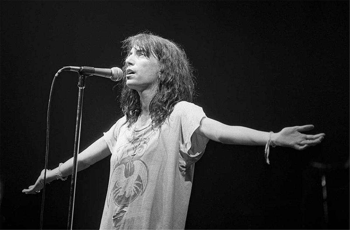 Patti Smith with arms outstretched at the microphone, photographed by Charlyn Zlotnik, 1978.