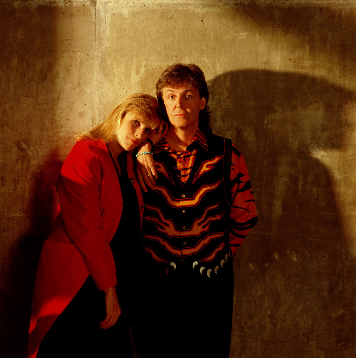 Paul and Linda McCartney stand close together backstage in warm, subdued light. Photograph by Timothy White, Chicago, Illinois, 1989.